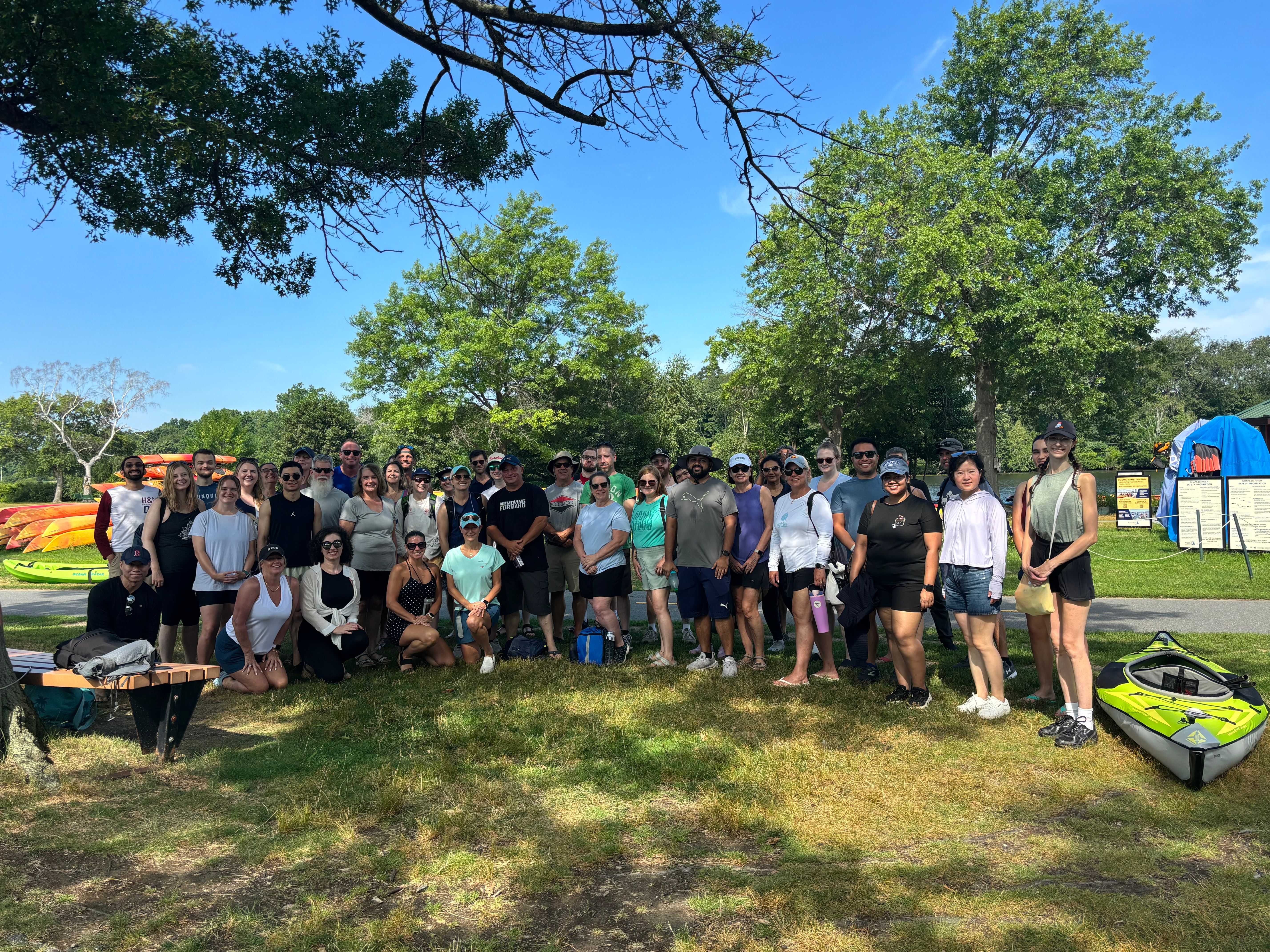 A group of people next to and in front of kayaks