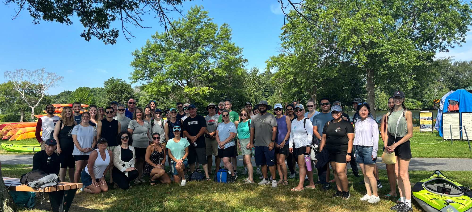 A group of people next to and in front of kayaks