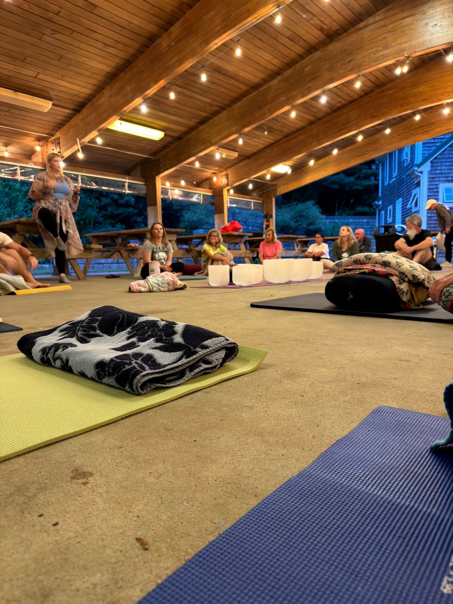 Mats, blankets and cushions spread across the pavilion floor under the lit wooden ceiling.