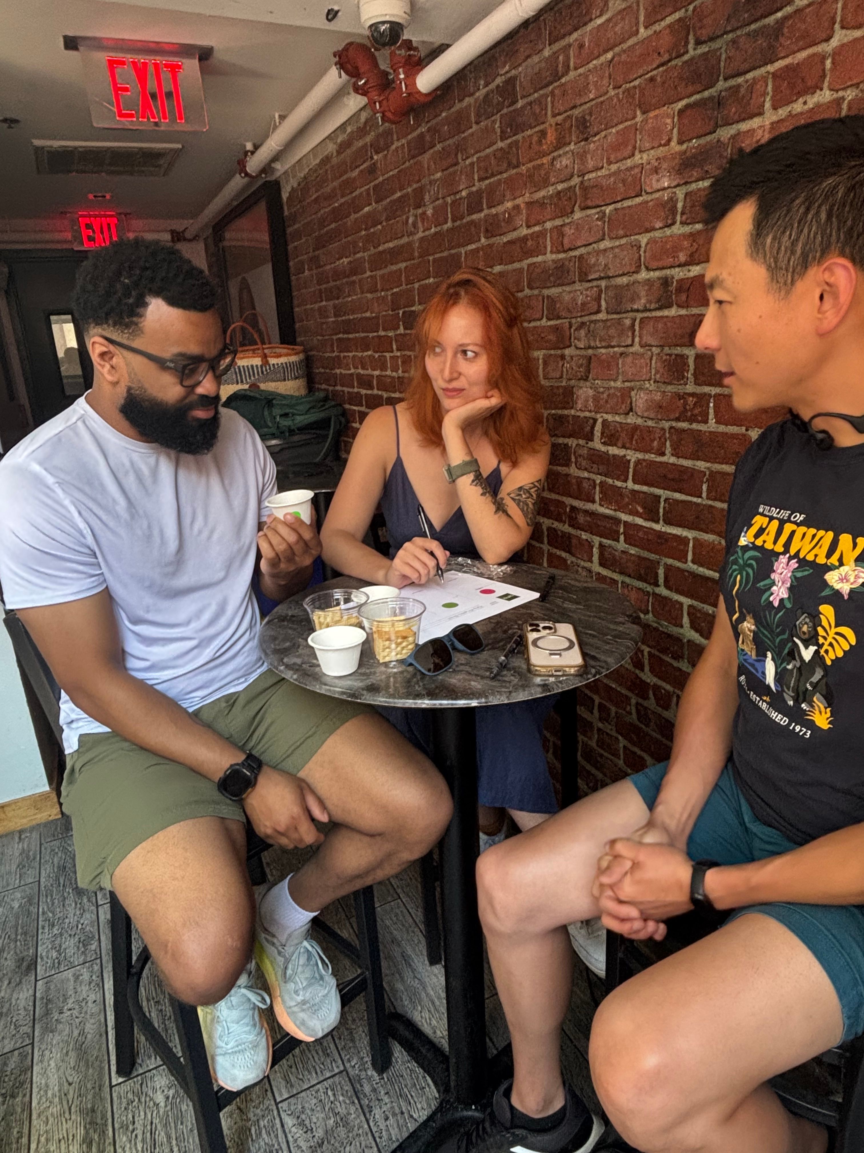 Three people seated at a coffee tasting.