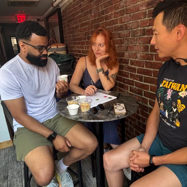 Three people seated at a coffee tasting.