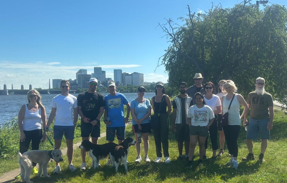 Group of people standing on the Esplanade with Boston in the background.