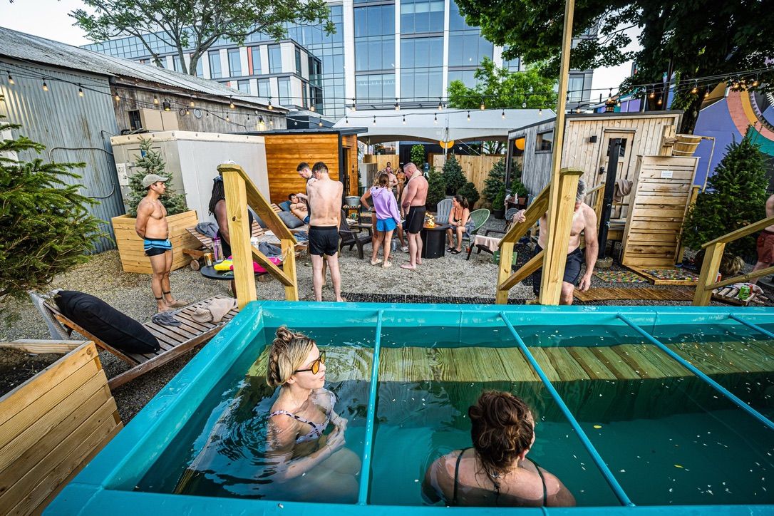 Two people in a cold plunge and multiple people int he background.