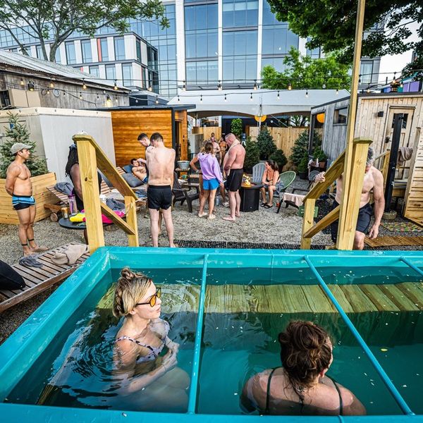 Two people in a cold plunge and multiple people int he background.