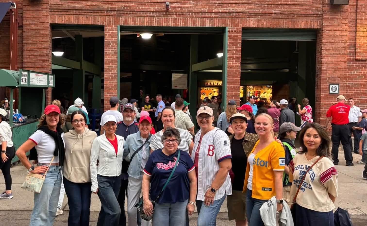 A group of women standing in front of the entrance to Fenway Park.
