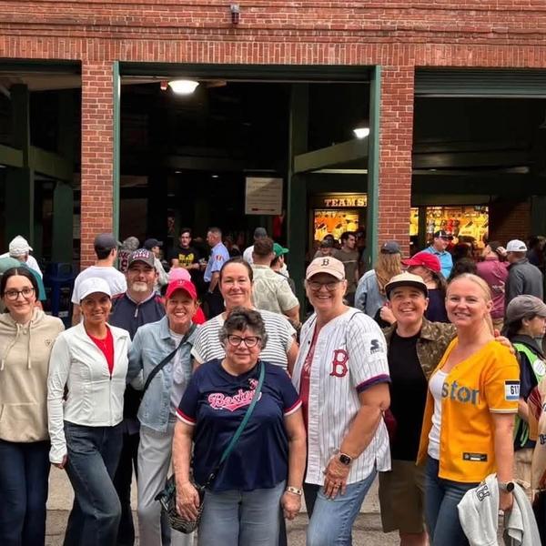 A group of women standing in front of the entrance to Fenway Park.