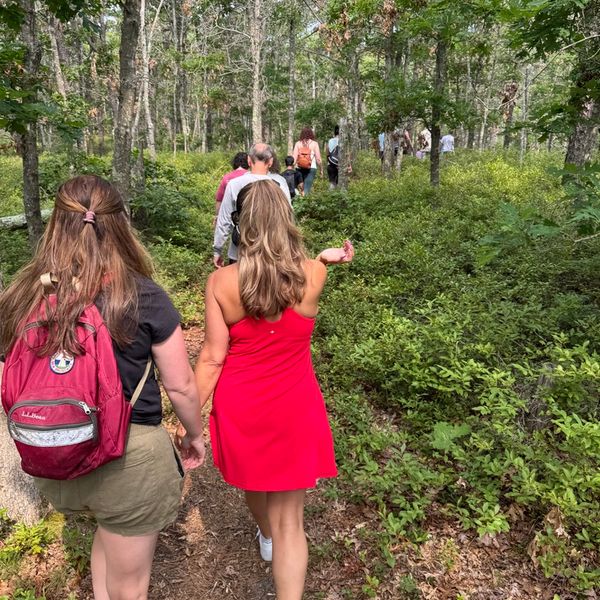 Woman pointing while hiking with a larger group of people.