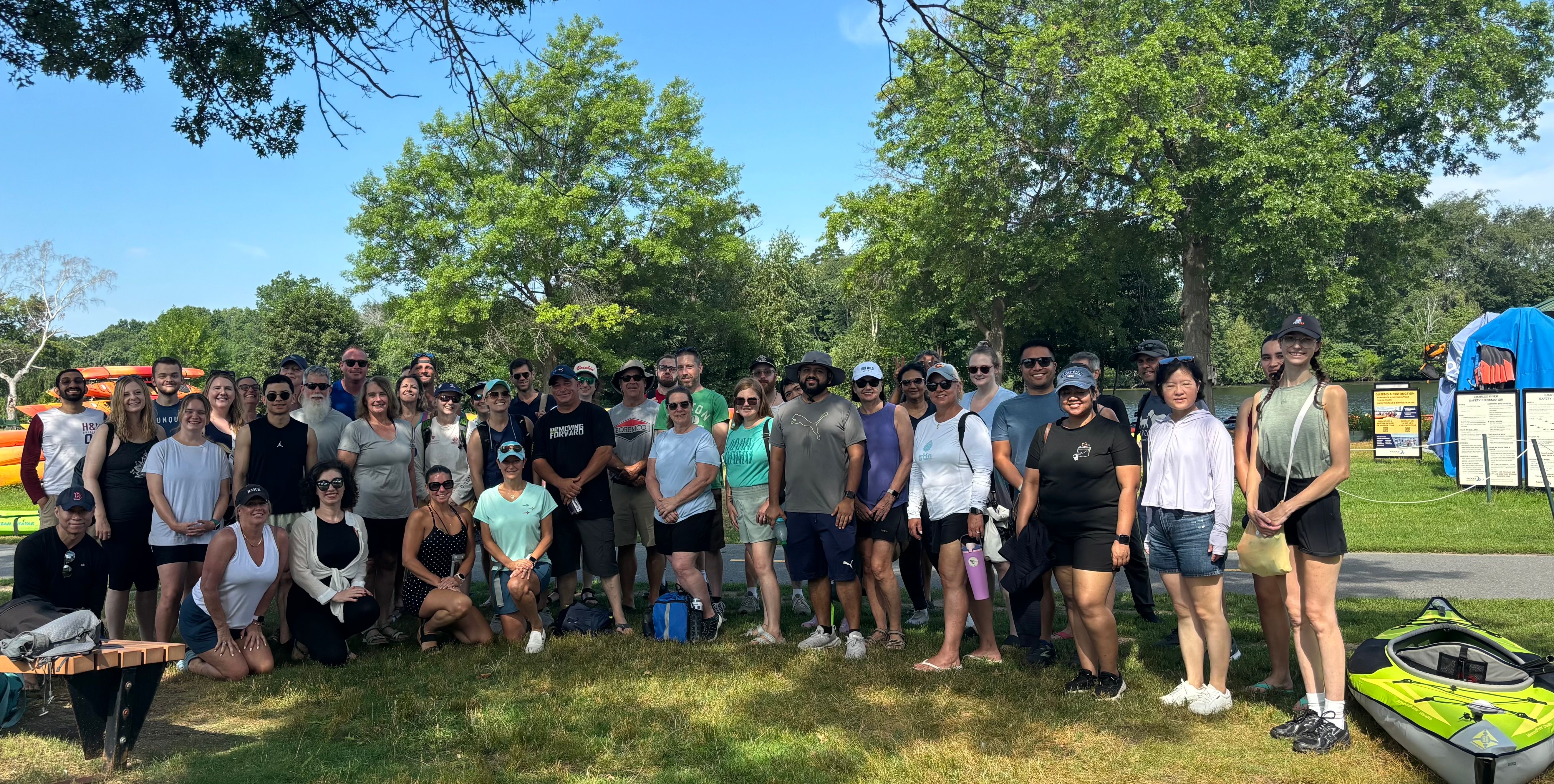 Large group of people in the shade with a kayak next to them.