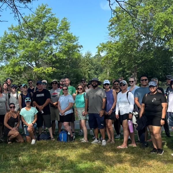 Large group of people in the shade with a kayak next to them.