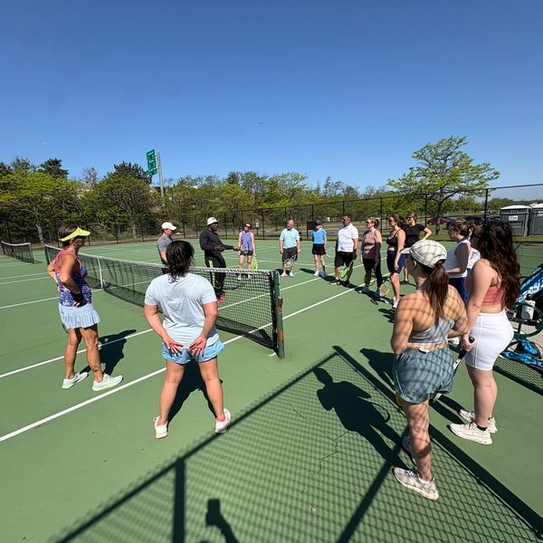 Circle of people around a tennis net.