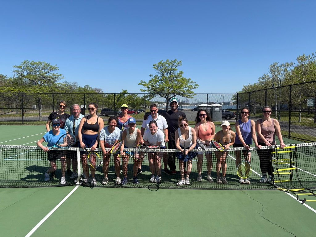 Members leaning against the net of a tennis court after a clinic.