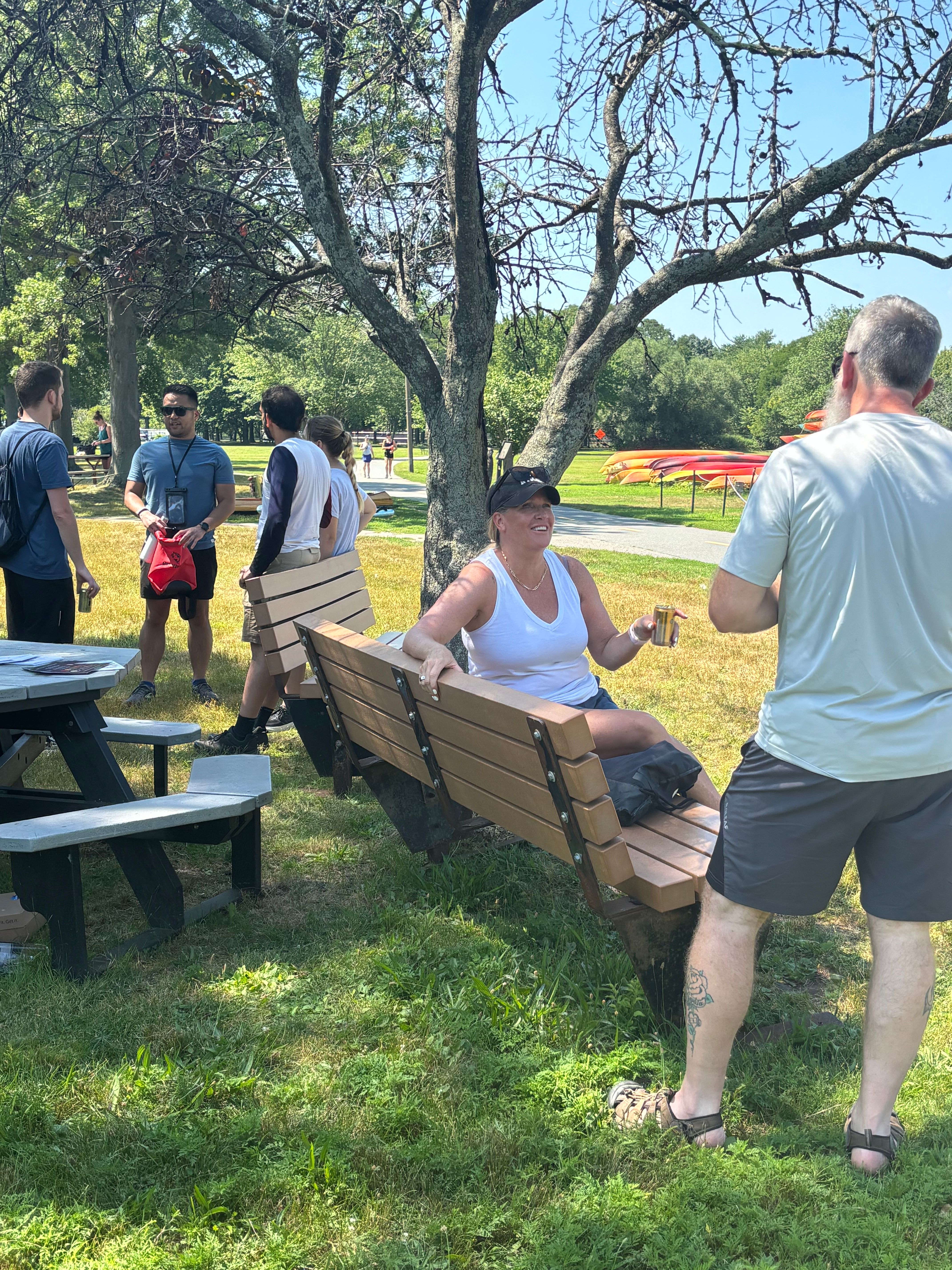 Woman on a bench holding an NA beverage talking to a man.
