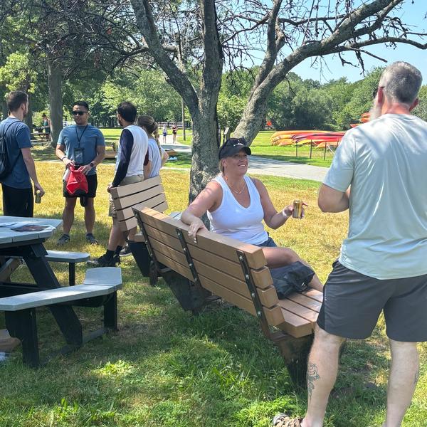 Woman on a bench holding an NA beverage talking to a man.