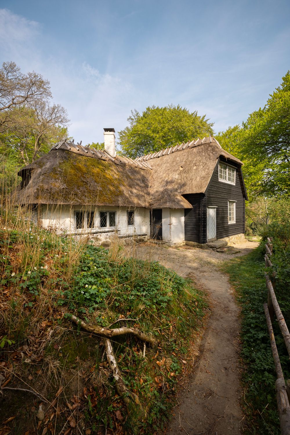 Det Norske Hus i Liselund Park set udefra – en langstrakt bygning i bindingsværk og mørkbejdset træ med stråtag.