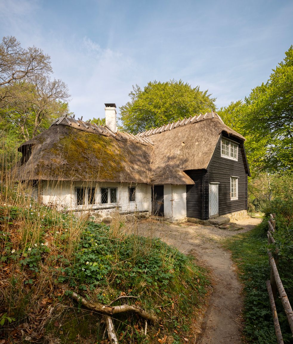 The Norwegian House in Liselund Park seen from outside – a long half-timbered building with dark-stained wood and a thatched roof.