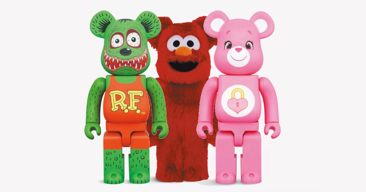 A group of Bearbricks in green, red, and pink in front of a very light gray background.