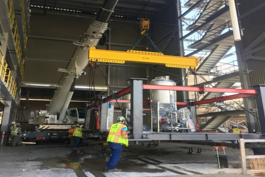 Crane lifting an equipment skid into a battery manufacturing plant during a Sack Company installation