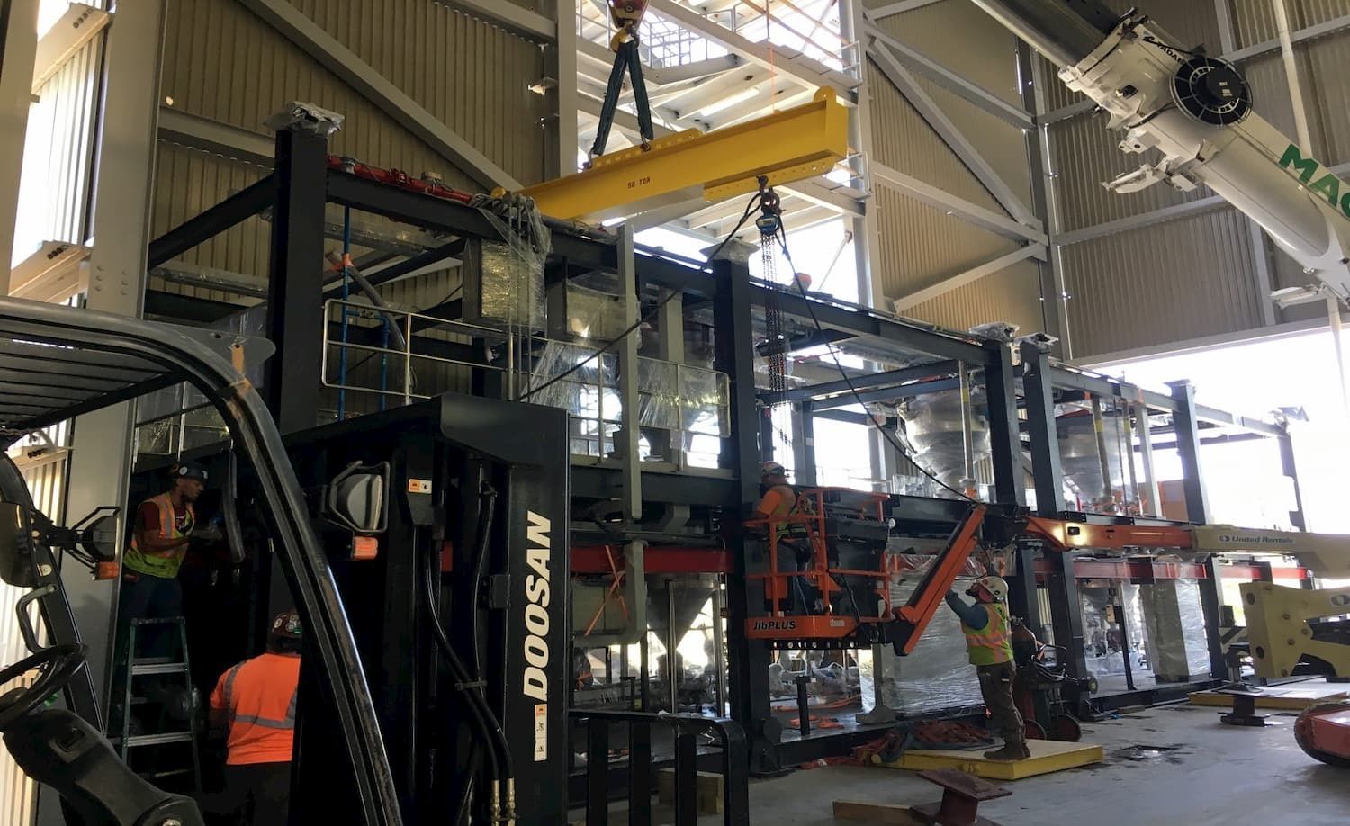 Sack Company crew moving large industrial equipment with a forklift and crane.