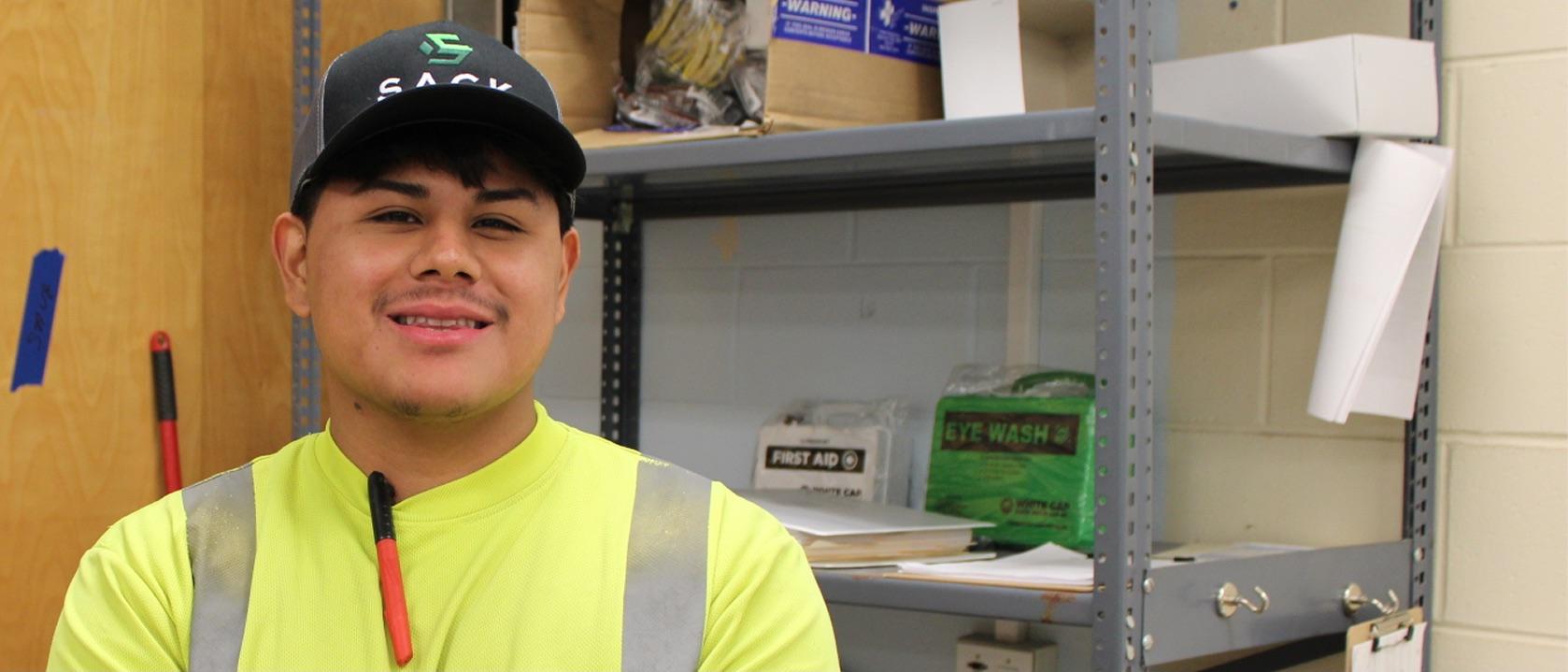 Smiling Sack Company worker in a cap and safety vest.