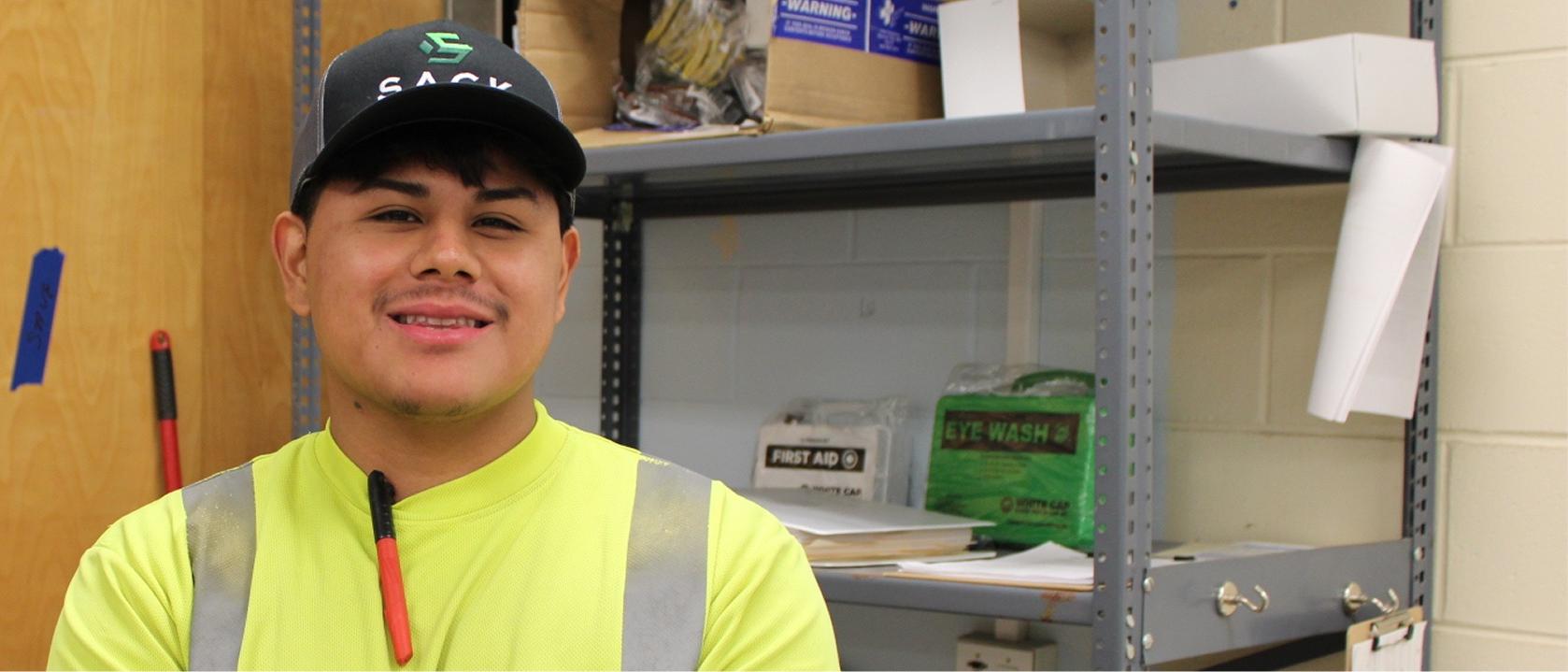 Smiling Sack Company worker in a cap and safety vest.