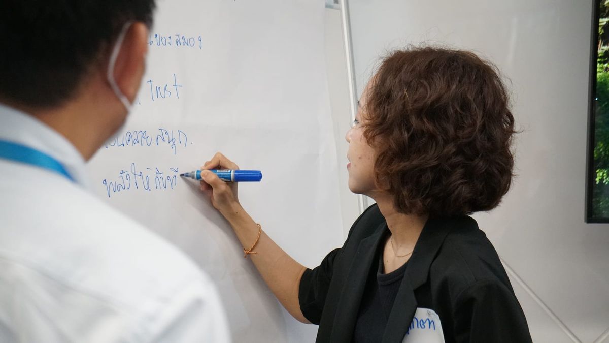 ผู้เข้าอบรมเขียนสรุปเรื่อง Trust บนฟลิปชาร์ตในหลักสูตร Leading with Trust for High-Performance Teams