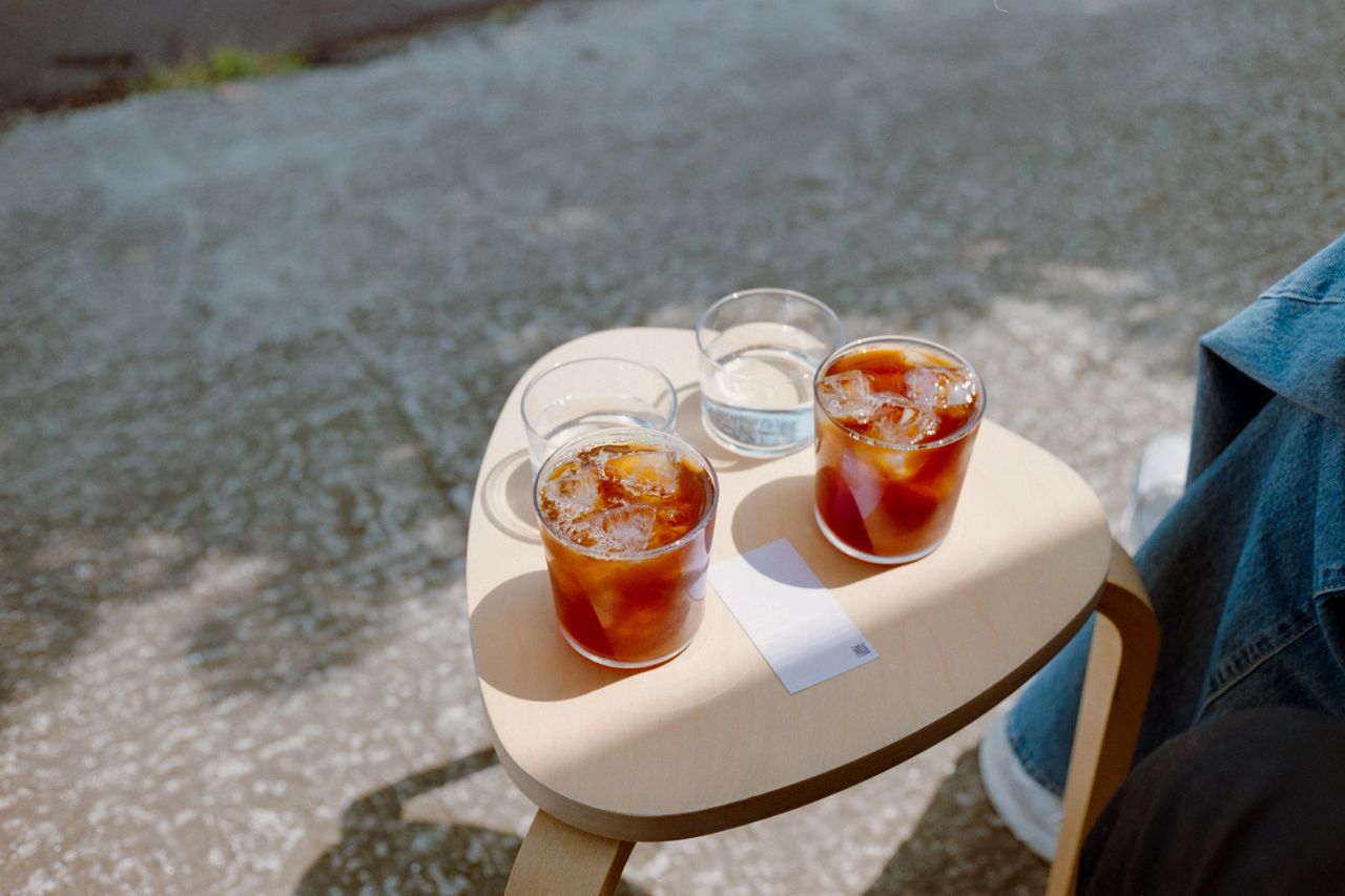 Two iced filter coffees on a table with sunlight.
