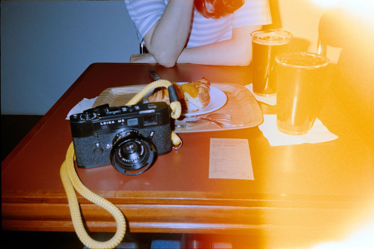 Leica M5, two iced filter coffees and a peach pastry on a table.