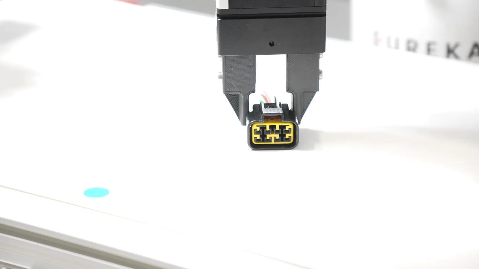 Parallel gripper holding a small connector during a robotic picking demonstration