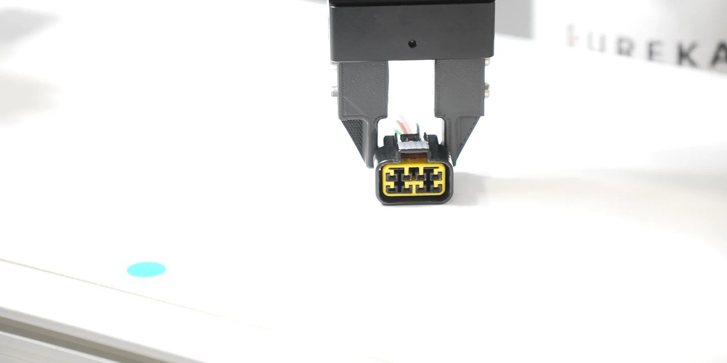 Parallel gripper holding a small connector during a robotic picking demonstration
