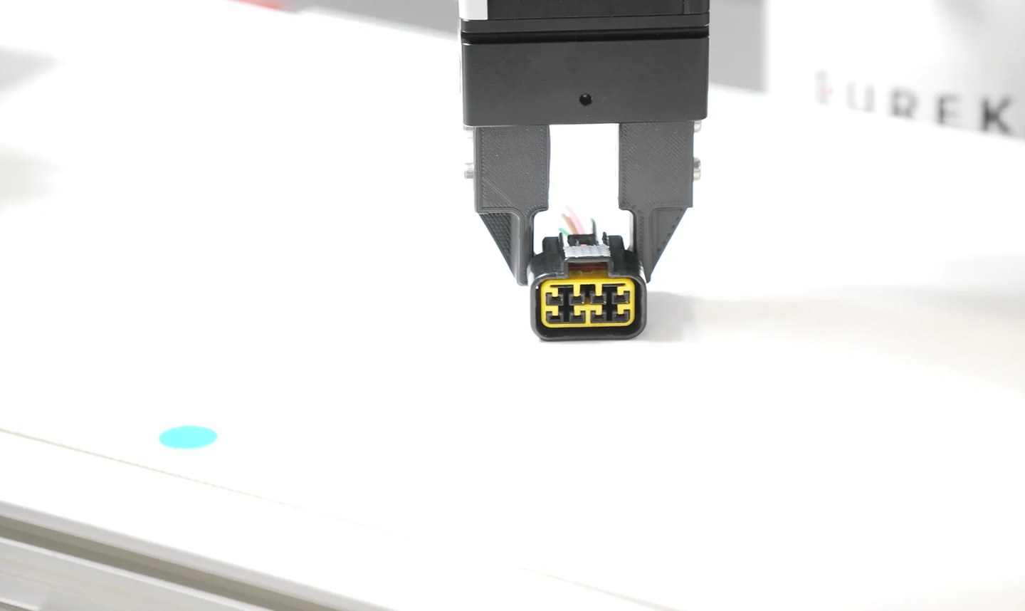 Parallel gripper holding a small connector during a robotic picking demonstration