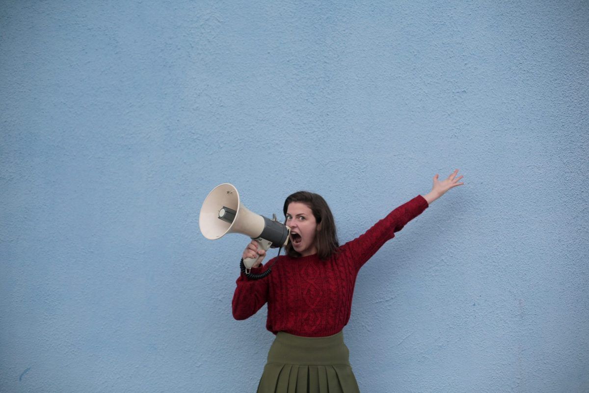 Una chica gritando en un megáfono.
