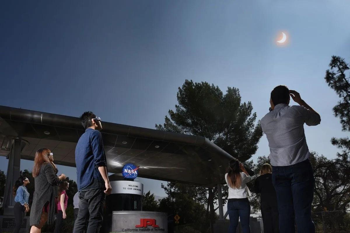 Viewers outside at JPL wear eclipse glasses while watching a partial phase of the Sun.