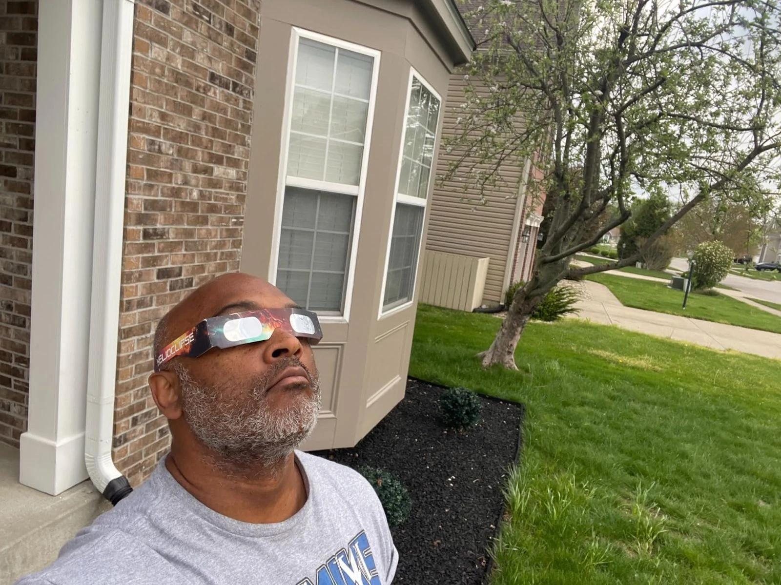 man watching solar eclipse with helioclipse glasses suburban home — people viewing the eclipse with protective glasses