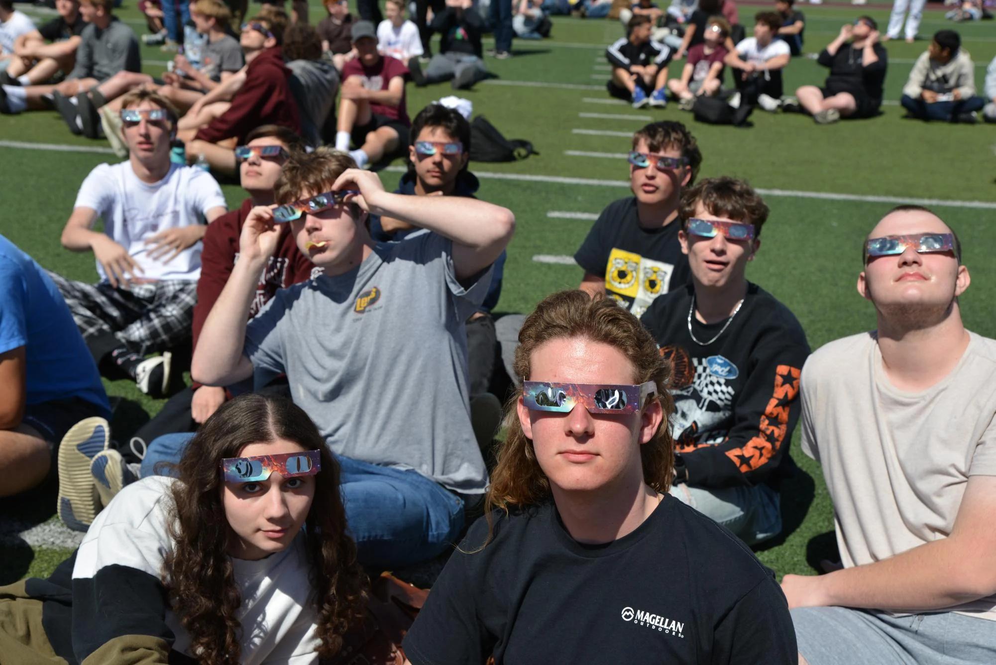 crowd of students watching eclipse with glasses school field — people viewing the eclipse with protective glasses