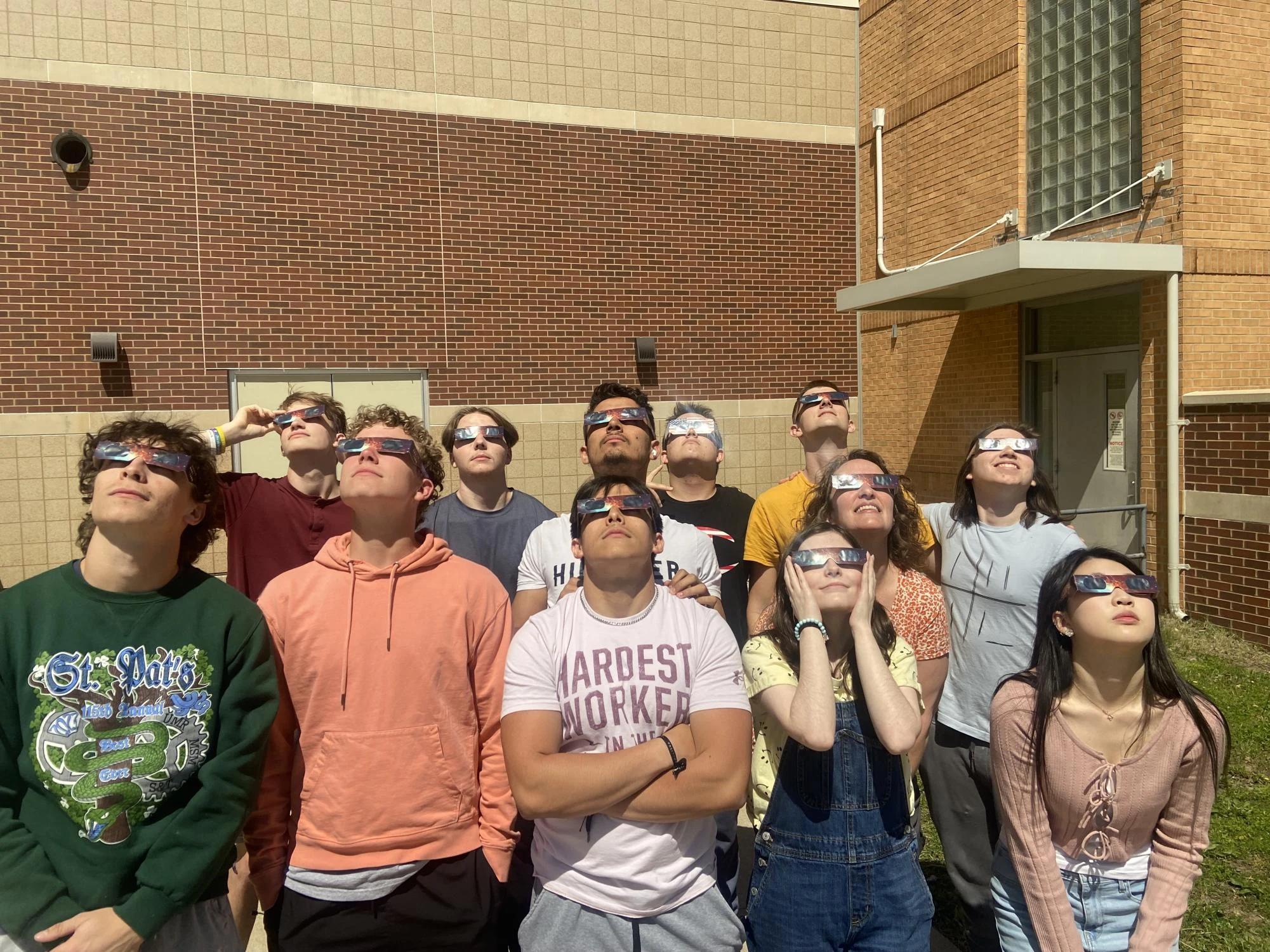 smiling couple wearing solar eclipse glasses outdoor selfie — people viewing the eclipse with protective glasses