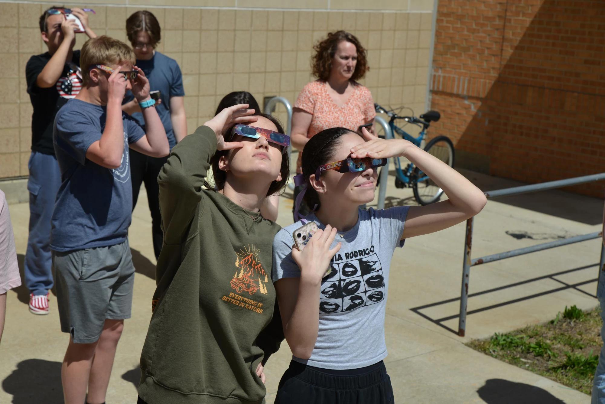 students looking at solar eclipse with helioclipse glasses school campus — people viewing the eclipse with protective glasses