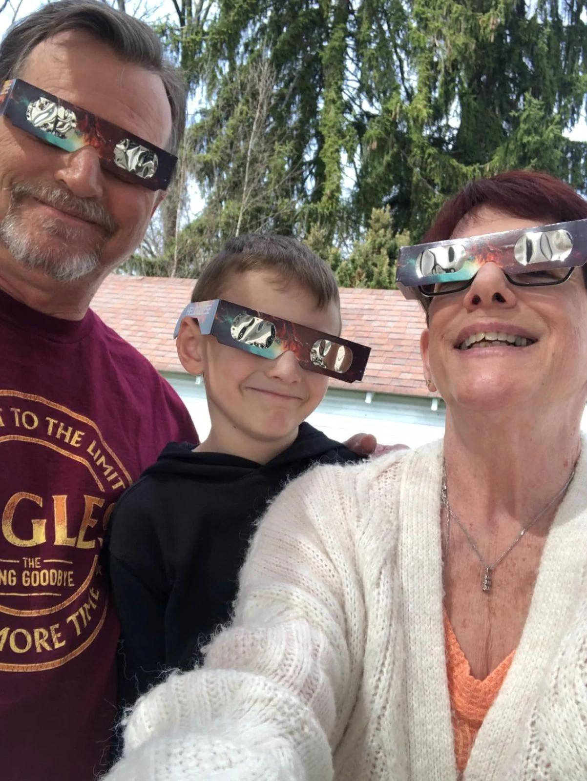 family selfie parents and child wearing solar eclipse glasses backyard — people viewing the eclipse with protective glasses