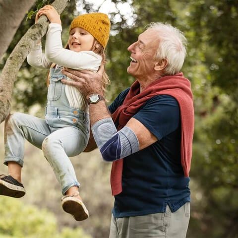 Grandpa wearing the Bauerfeind EpiTrain Elbow Bandage while playing with grandchild