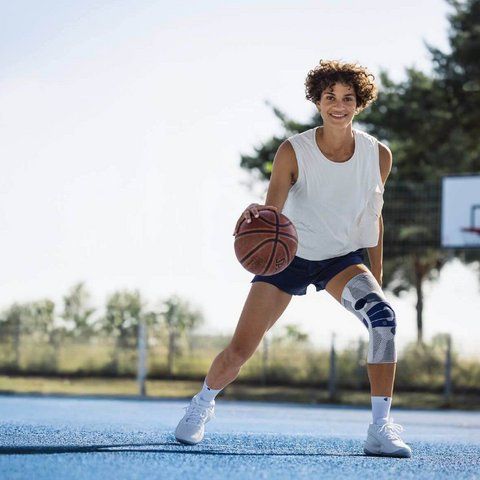 Woman playing basketball wearing the Bauerfeind GenuTrain p3