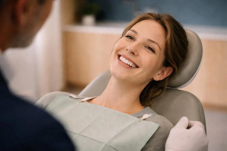 Fornøyd pasient med strålende smil i tannlegestolen hos Akademisk Tannklinikk