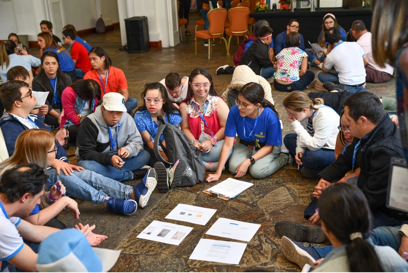 Image of people with Down syndrome sitting on the floor with an FIADOWN event coordinator