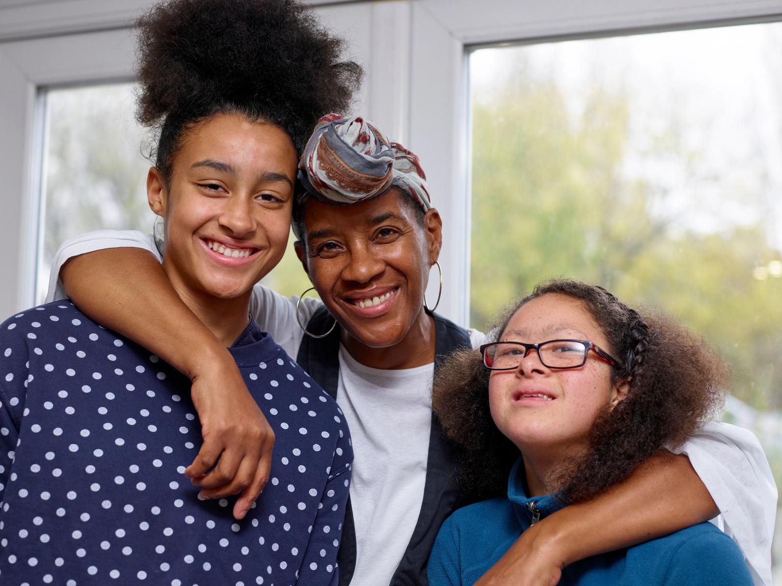 A person with Down syndrome smiling and standing with two other people