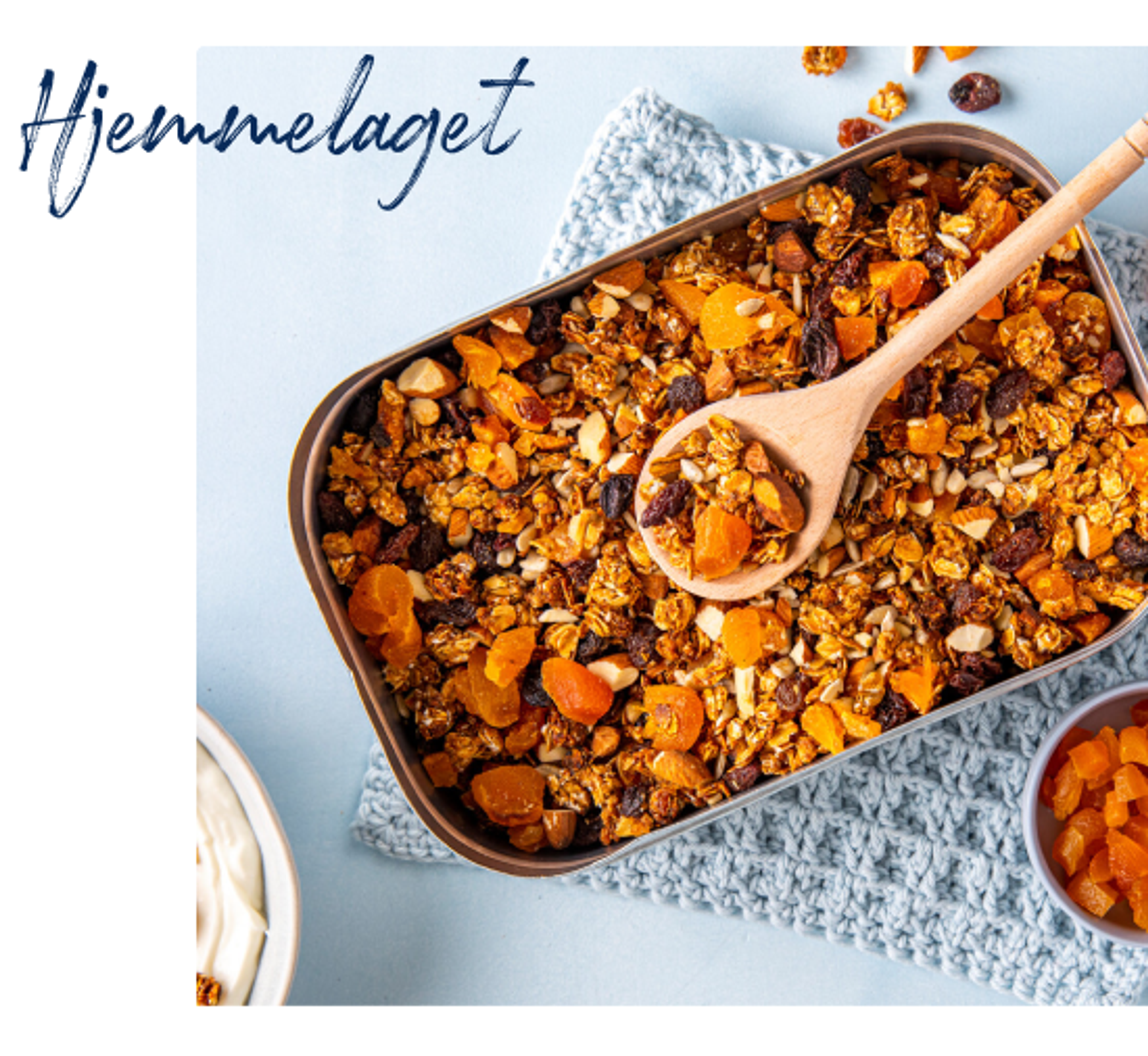 Hjemmelaget granola med tørket aprikos, rosiner og nøtter i en form, med en tresleiv oppi