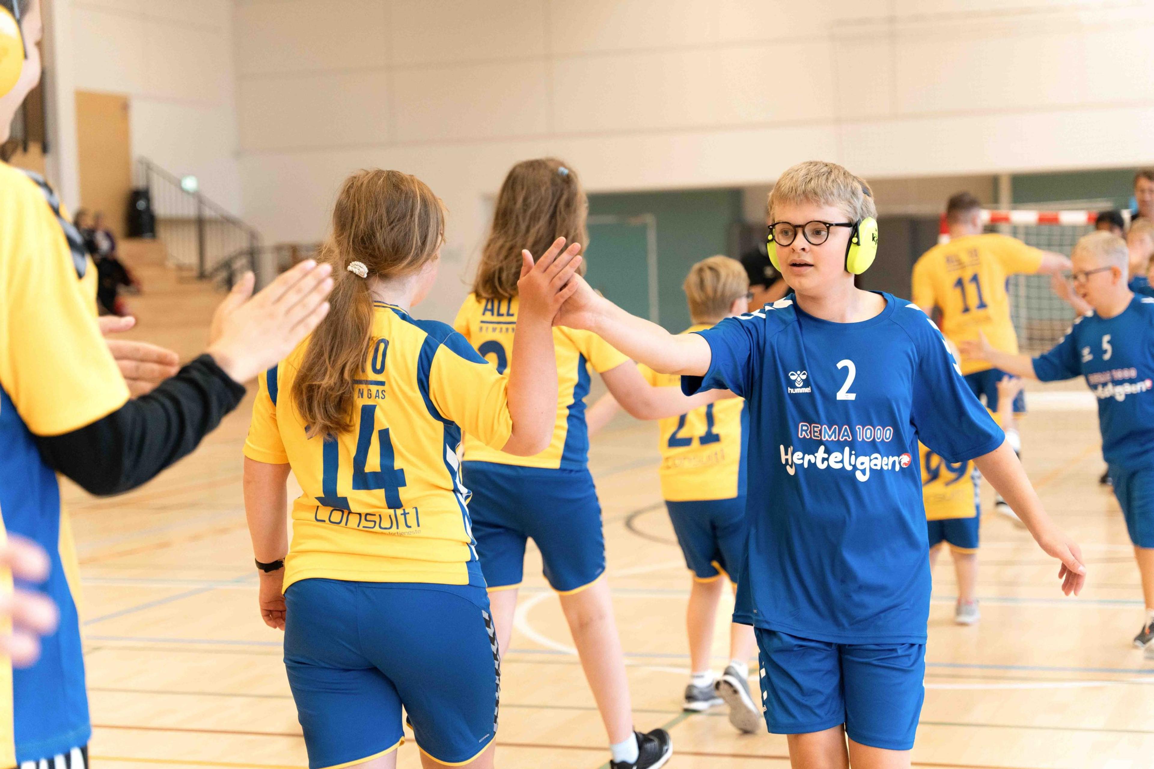 Deltakere i REMA 1000 Hjerteligaen gir hverandre high five i en idrettshall etter håndballaktivitet.