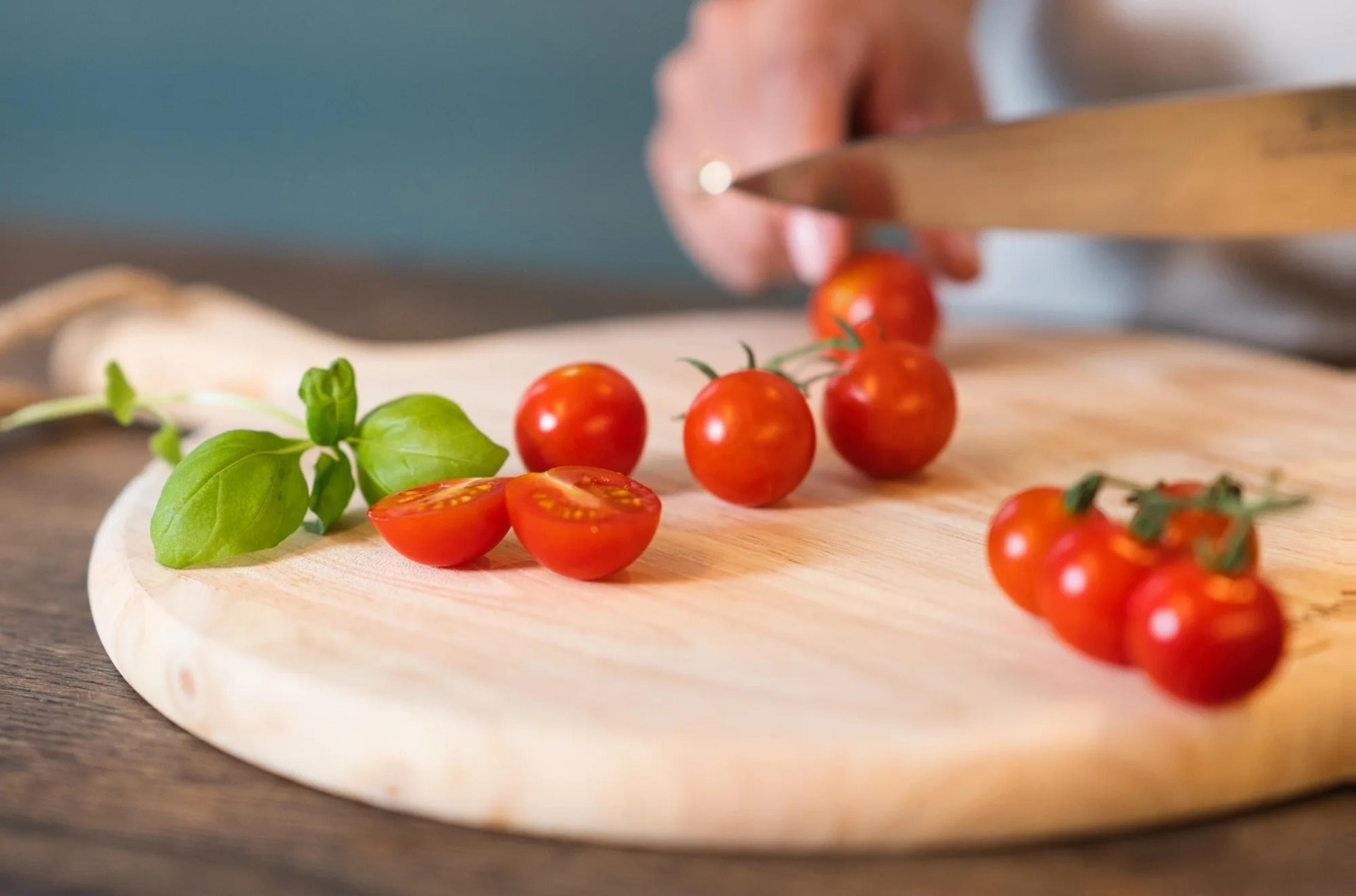 tomat av typen cherrytomater ligger på en fjel med basilikum ved siden av
