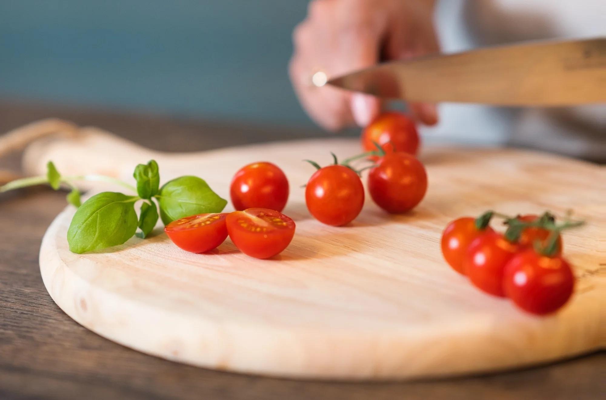 tomat av typen cherrytomater ligger på en fjel med basilikum ved siden av