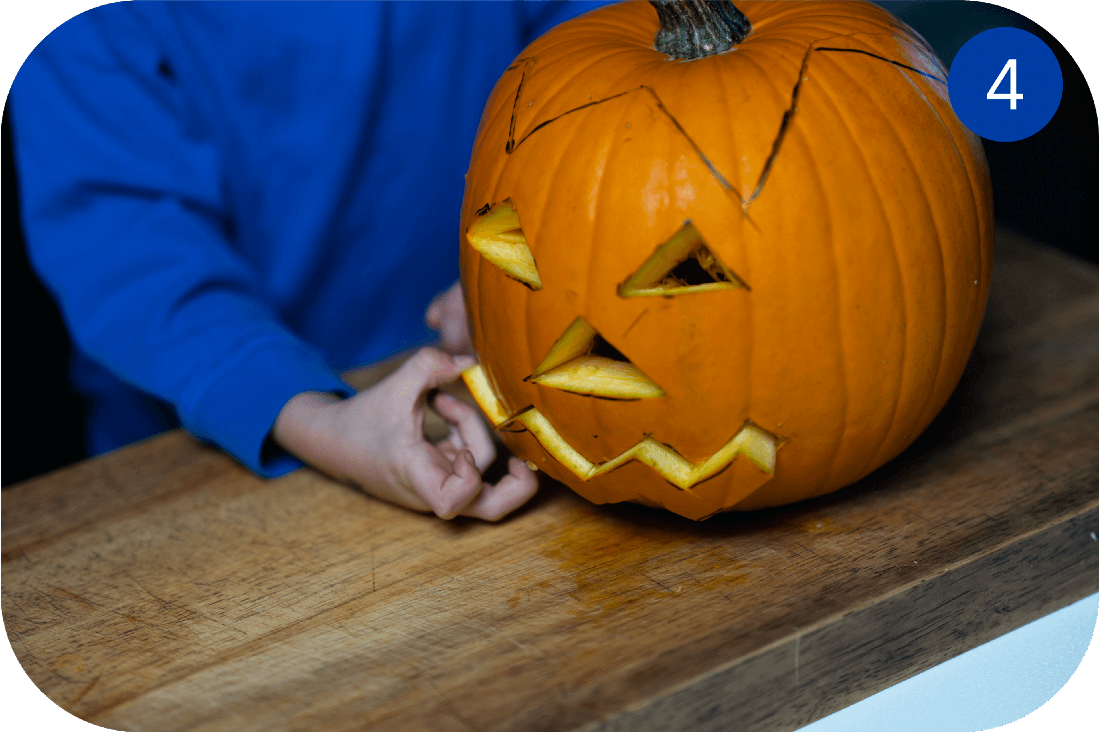 Ferdig utskåret Halloween-gresskar med trekantede øyne og taggete munn på et bord.
