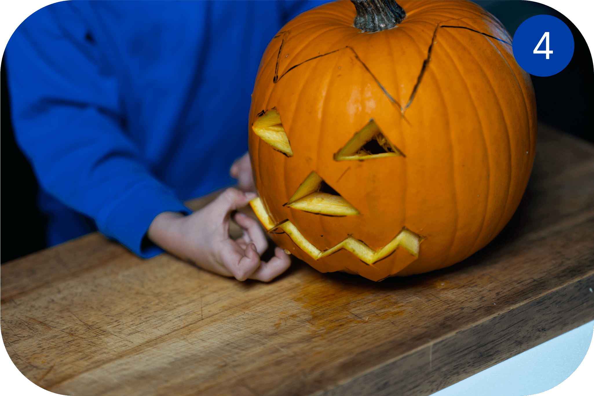 Ferdig utskåret Halloween-gresskar med trekantede øyne og taggete munn på et bord.