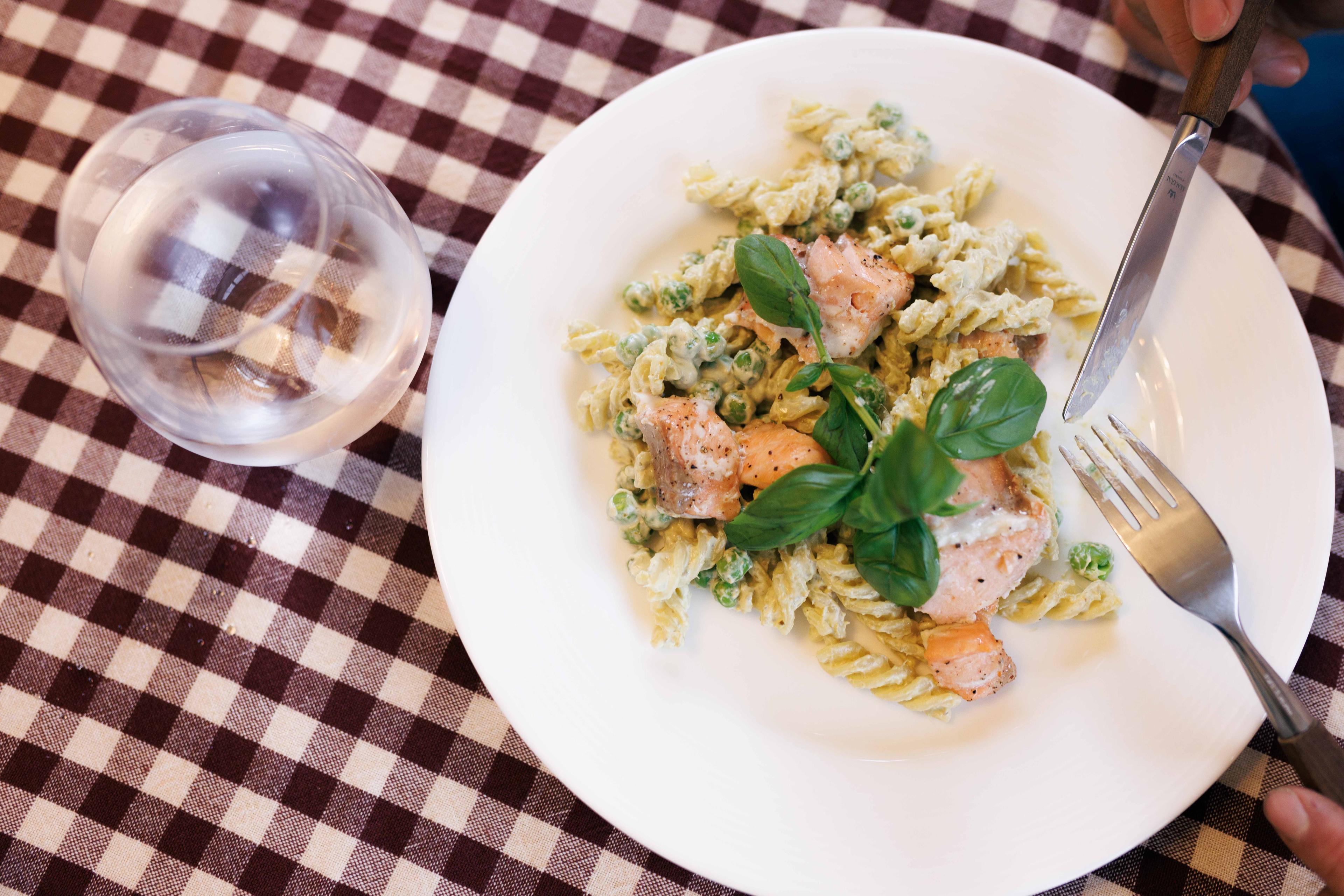 Bilde av pasta med laks på bordet med et glass vann