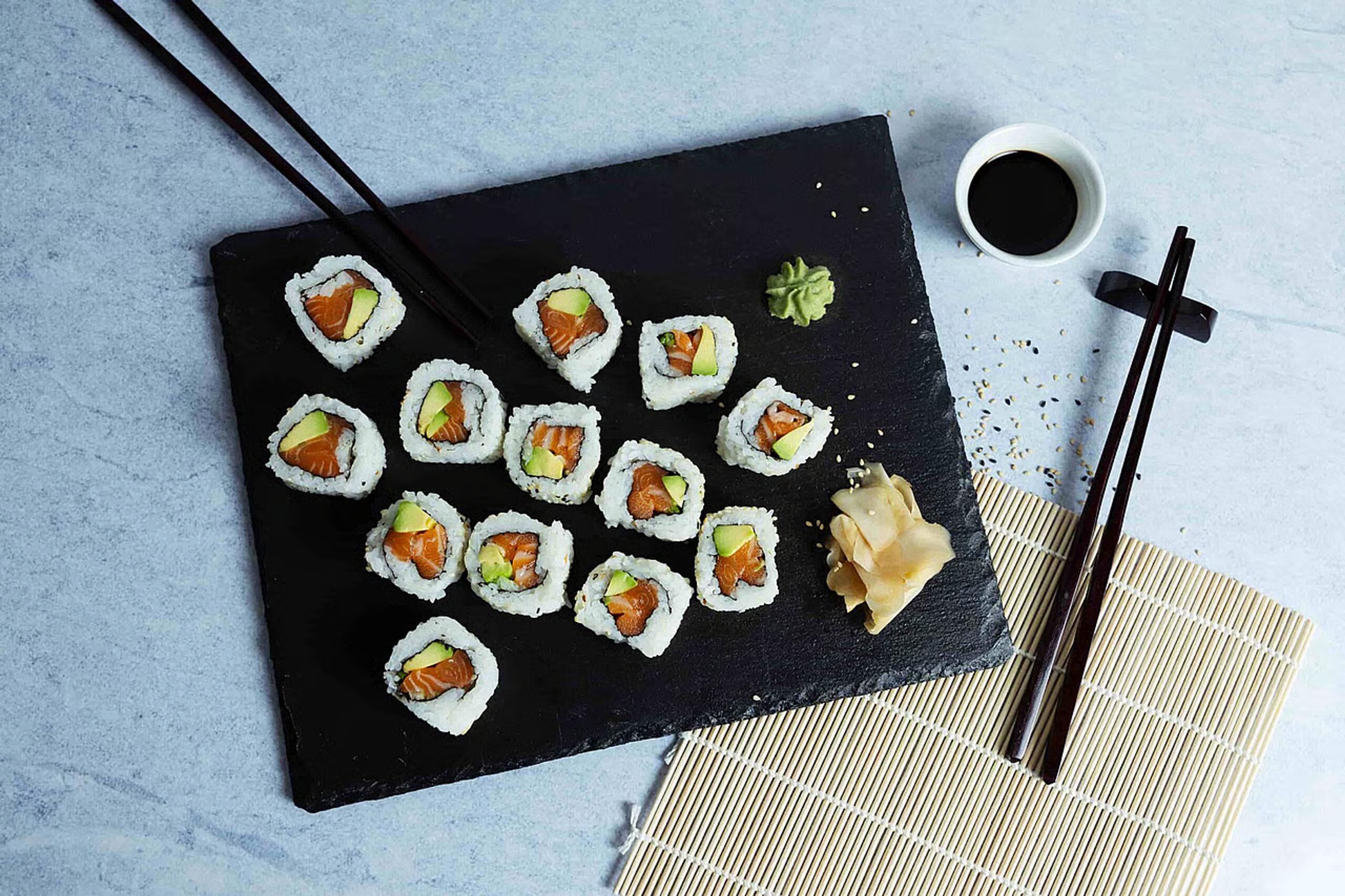 Lakse maki servert på steinfat med spisepinner og soyasaus ved siden av. 